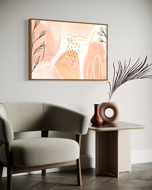 after the rain botanical wall art. soft pastel colours of apricot and blush pink combined with painted leaves and rain drops create a beautiful and unique abstract nature based artwork. artwork is hanging in a high quality canvas timber float frame above a lounge chair in a designer home.
