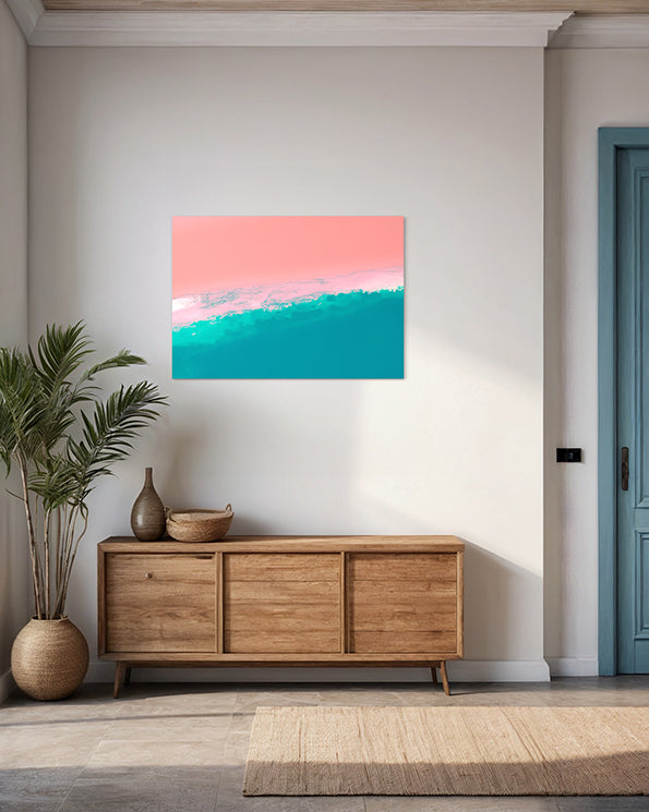 abstract artwork featuring ocean shoreline from above, pink sand meets the white wash in the middle of the frame with blue ocean waves, wall art print hanging in living room above side board