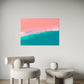 abstract artwork featuring ocean shoreline from above, pink sand meets the white wash in the middle of the frame with blue ocean waves, wall art hanging in living room above armchair and low lying white coffee table.